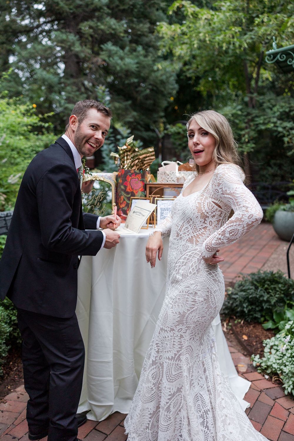 A couple shares a playful moment during their wedding photoshoot in a garden setting.
