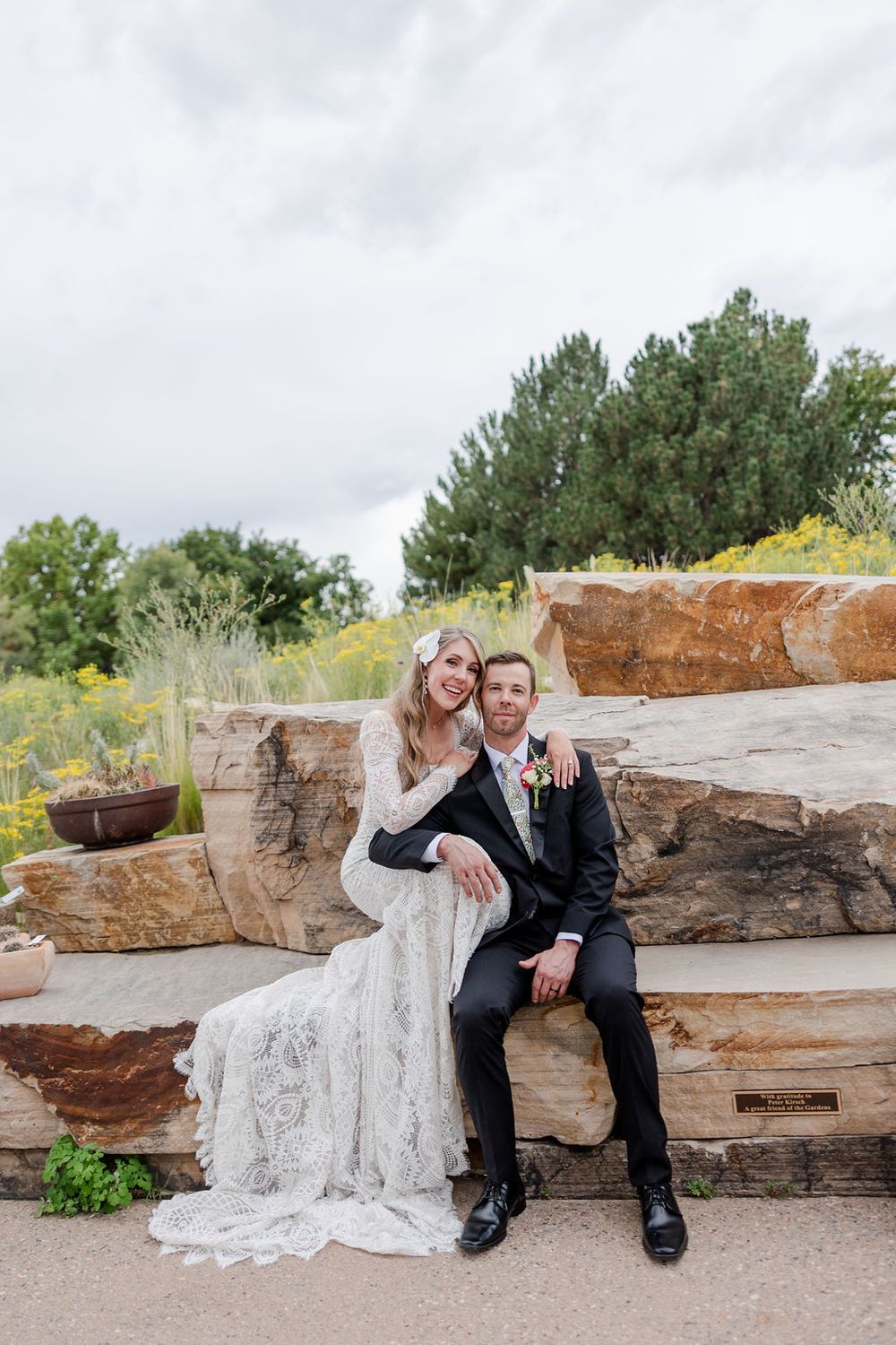 Couple poses together on rustic wooden logs in an outdoor setting.