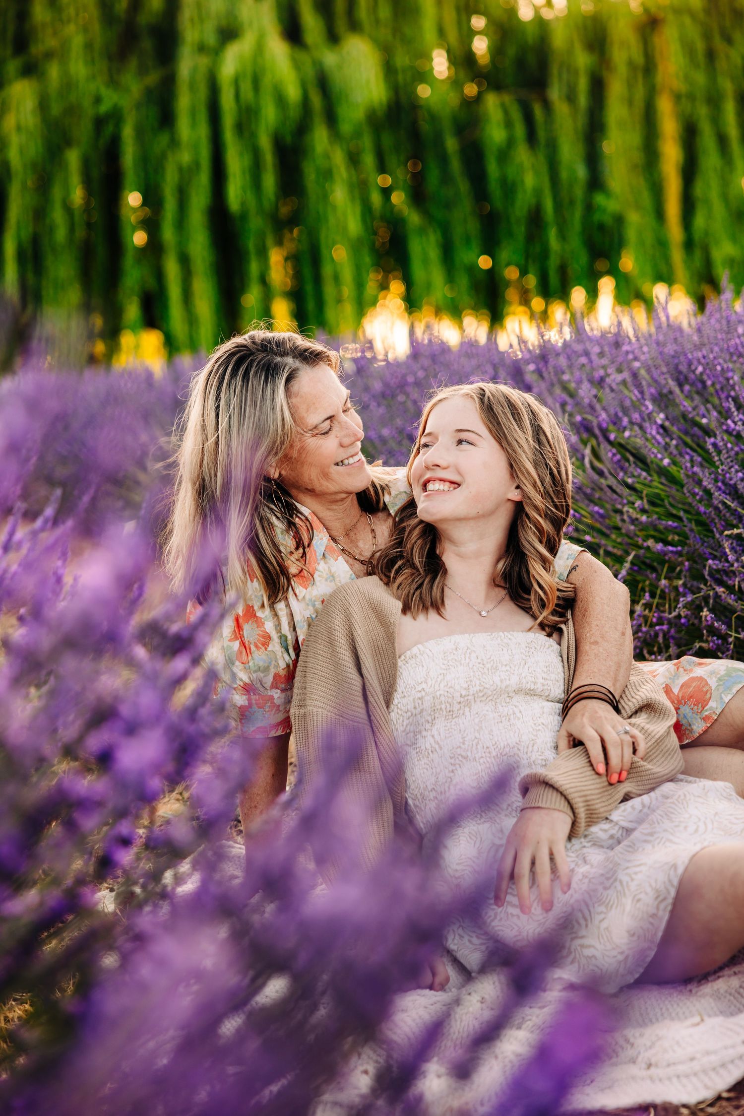 Friends enjoying a summer photoshoot together among purple lavender flowers at sunset.