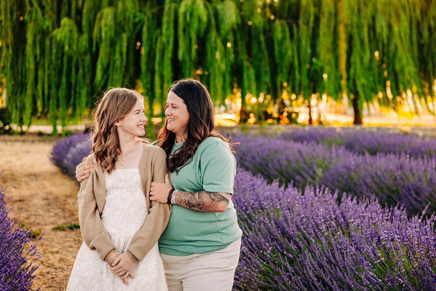 Two people share a joyful moment while walking through a vibrant lavender field on a sunny summer day.