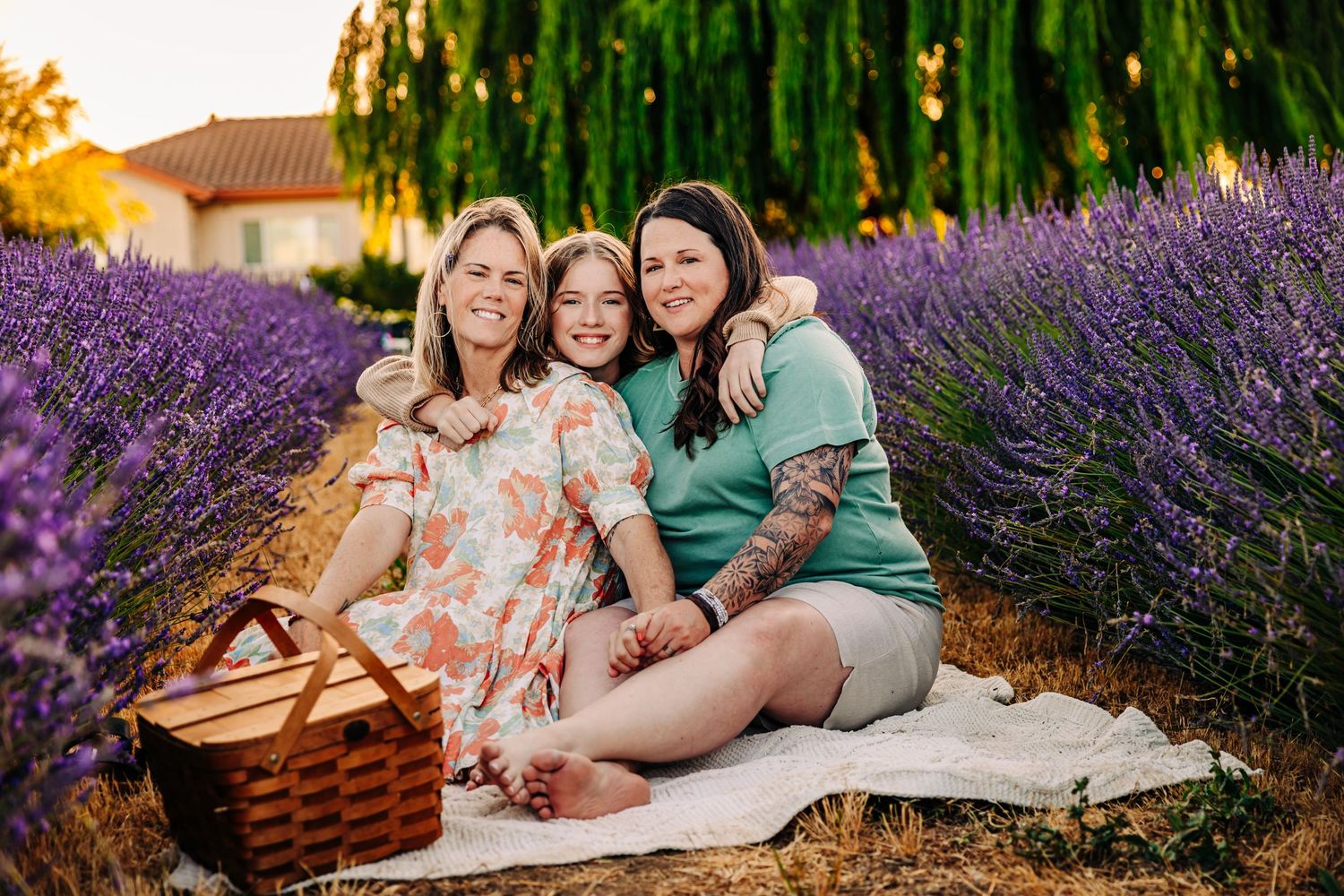 Group relaxing on a picnic blanket surrounded by lavender fields and willow trees.