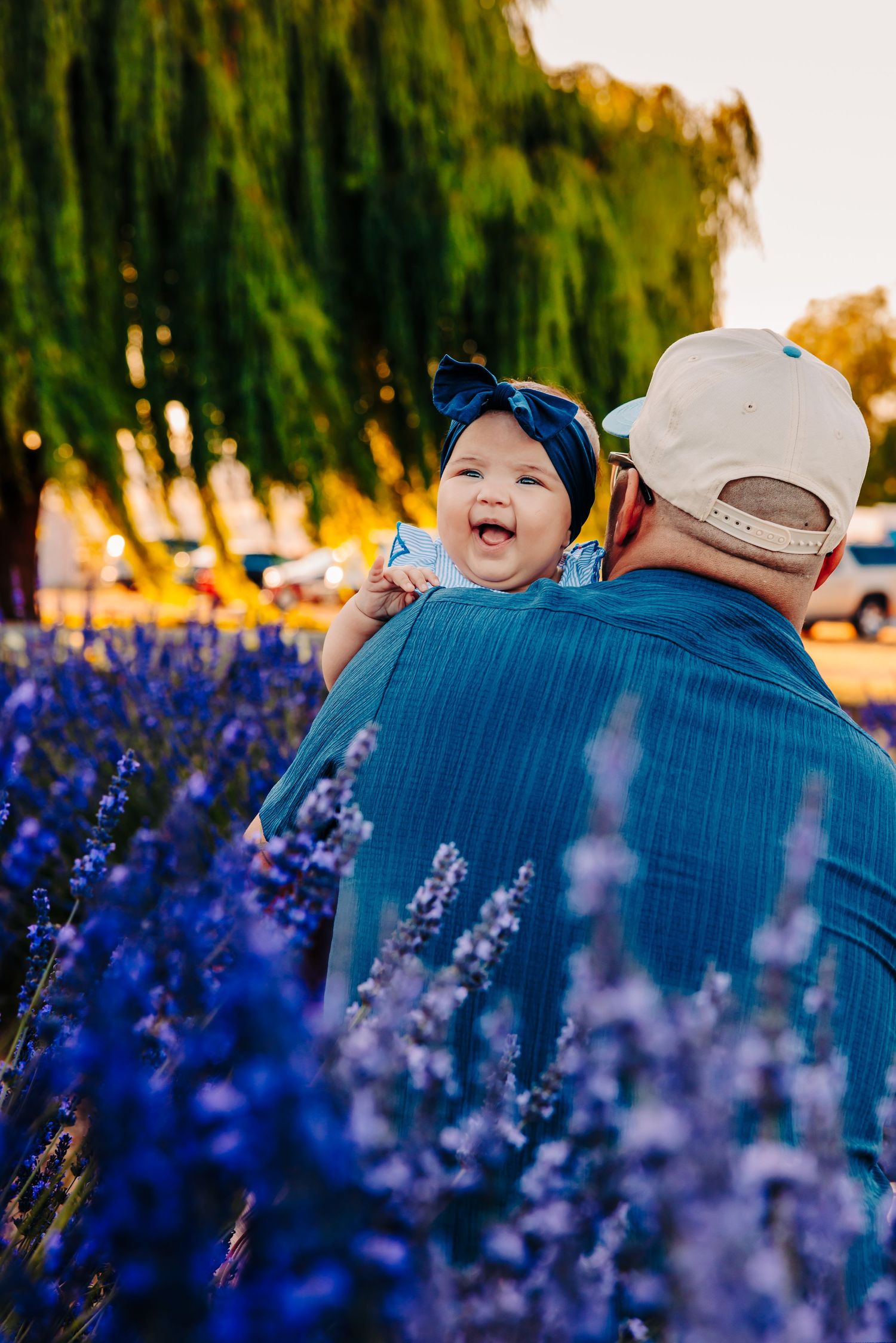 Family enjoying sunset moment together in field of blooming blue wildflowers during golden hour.