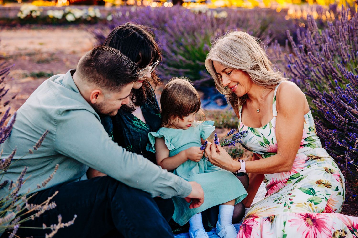 Candid family moments captured during an outdoor photo session among blooming purple flowers at golden hour.