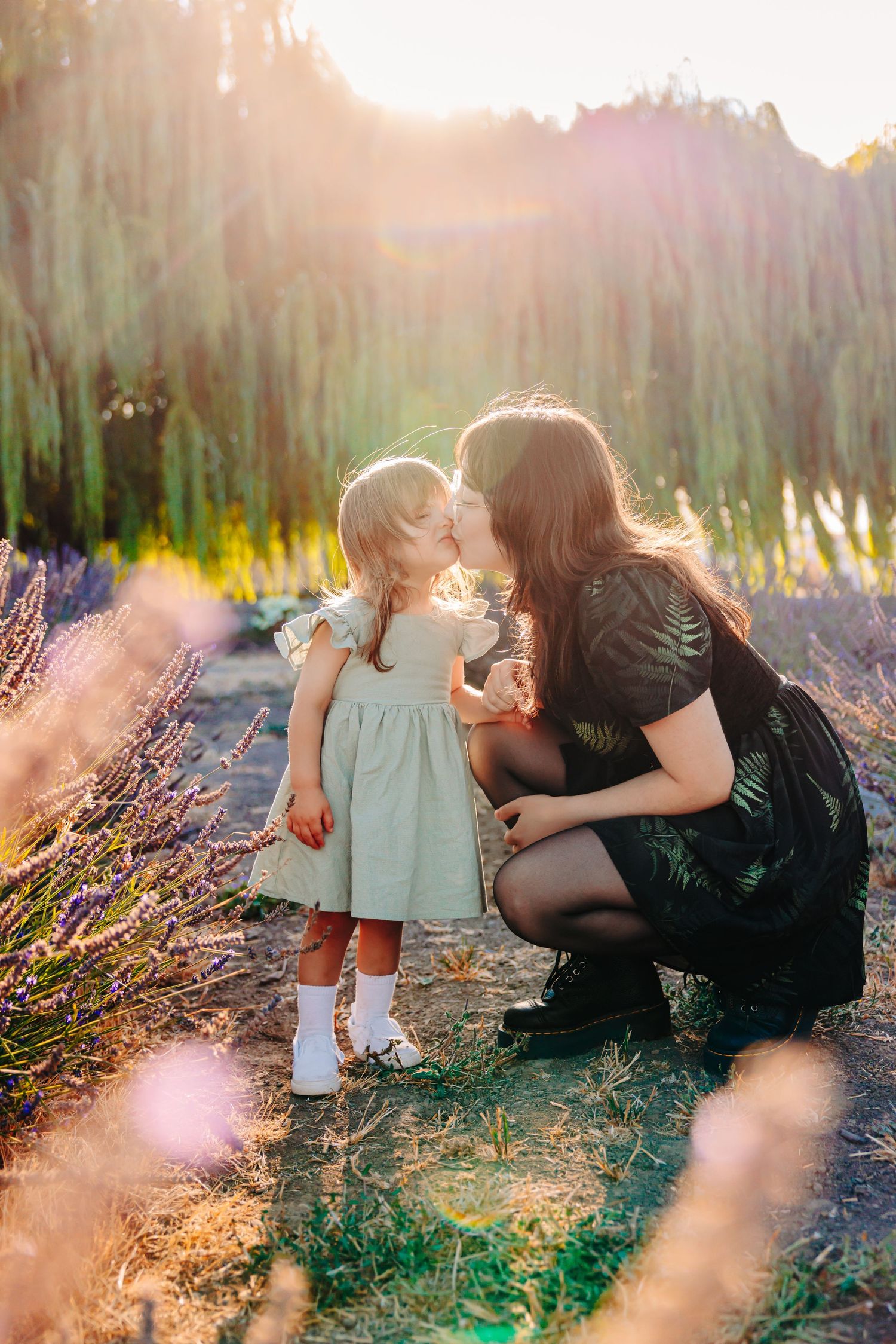 A tender moment captured in a lavender field at sunset with soft golden light filtering through the scene.
