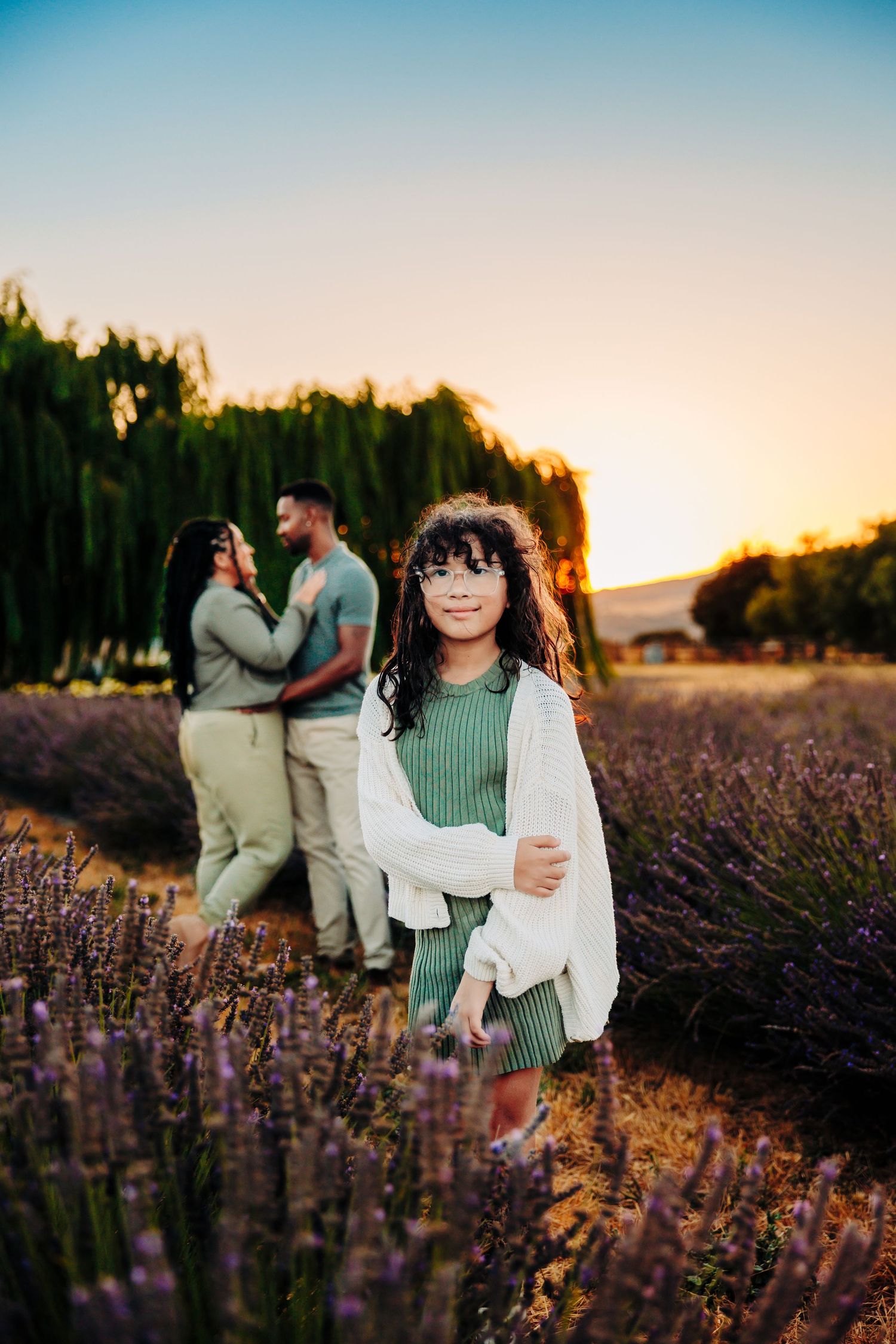 Romantic sunset photoshoot in a blooming lavender field with soft golden light and purple flowers.