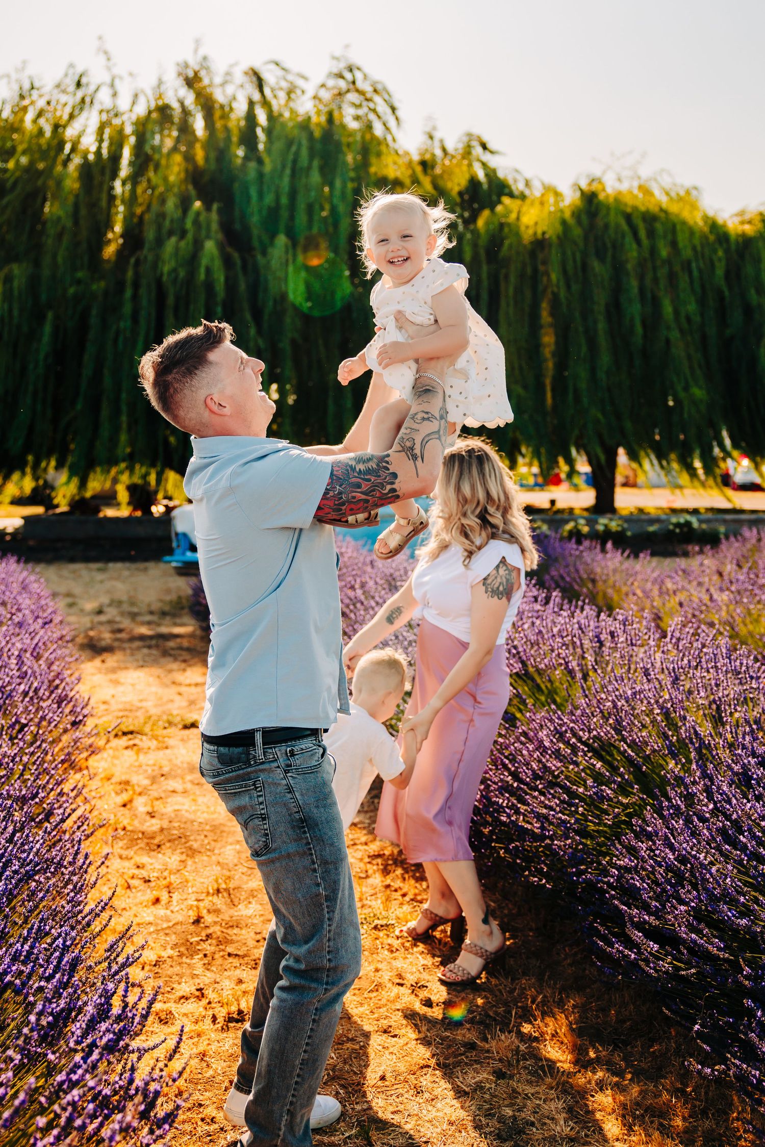 Family enjoying a playful moment together in a blooming lavender field at sunset.