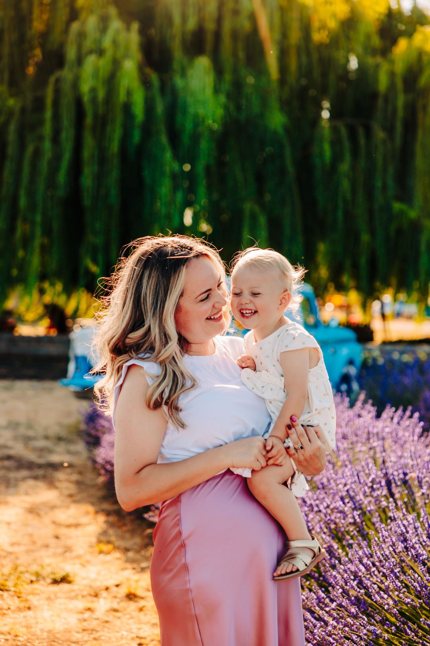 A joyful moment captured in a lavender field at sunset with warm golden light filtering through the trees.