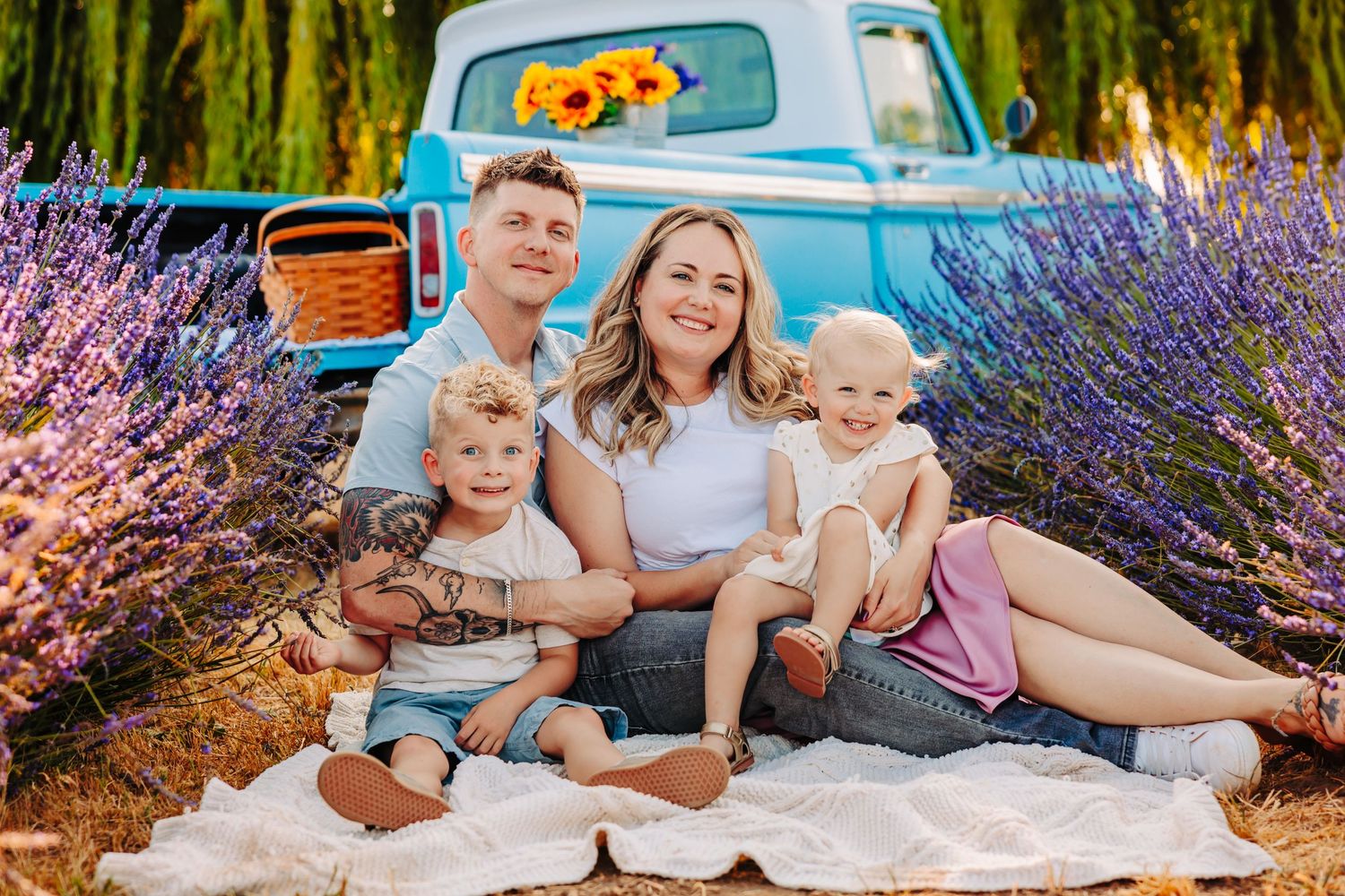 Family relaxes together on a blanket among blooming lavender fields on a sunny summer day.