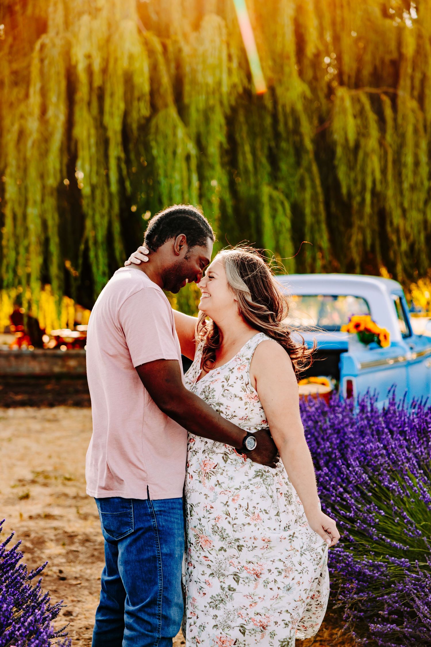 A couple shares intimate moments in a lavender field next to a vintage truck during a summer photoshoot.