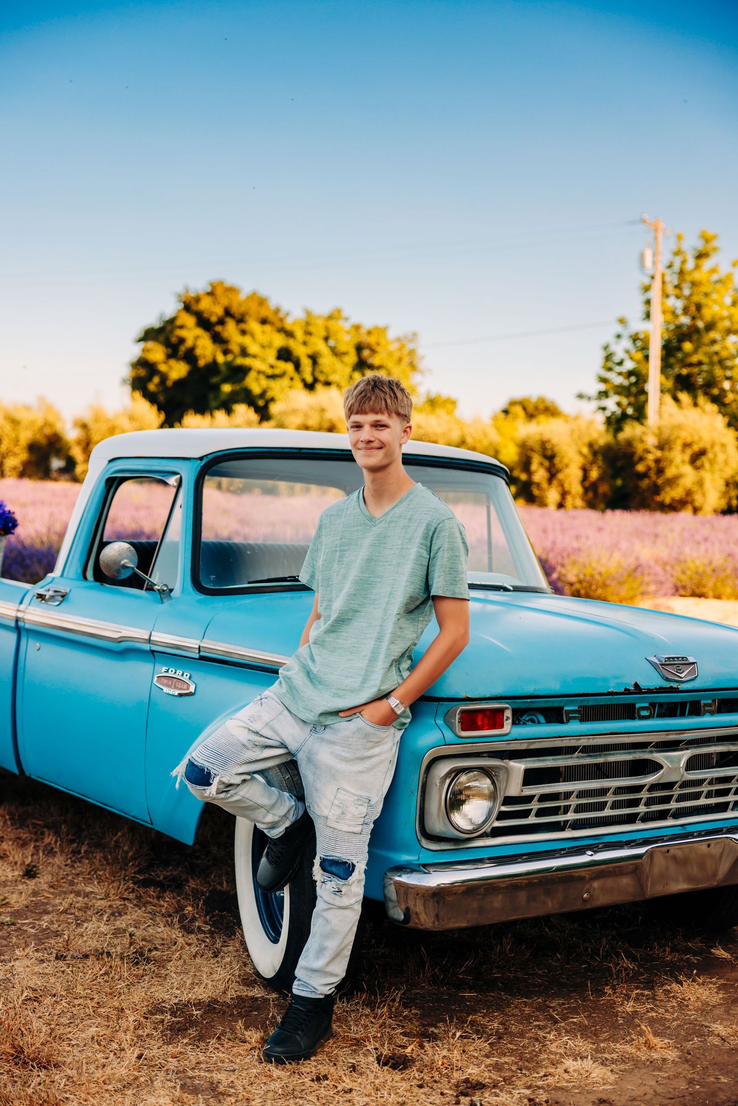 A vintage turquoise Chevrolet pickup truck sits in a golden field during sunset.