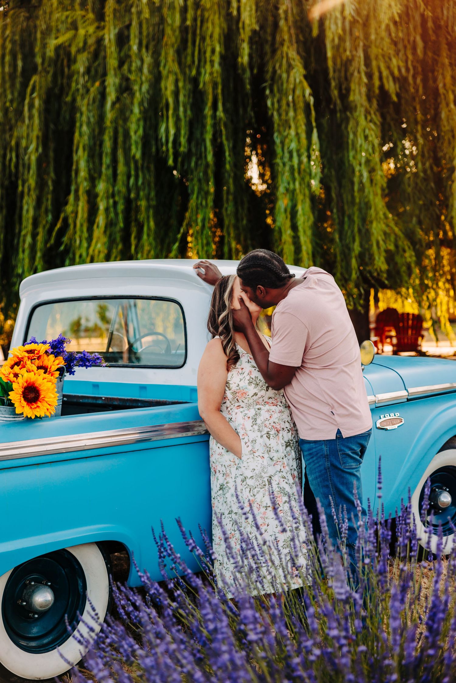 A romantic couple poses with a classic turquoise truck among blooming purple lavender and sunflowers.