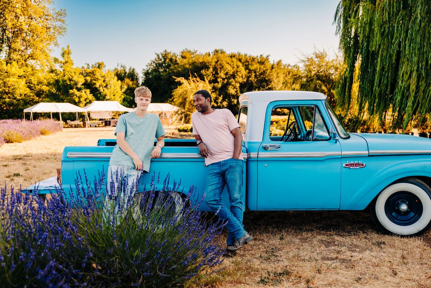 A classic turquoise vintage car parked near blooming lavender fields at sunset creates a nostalgic summer scene.