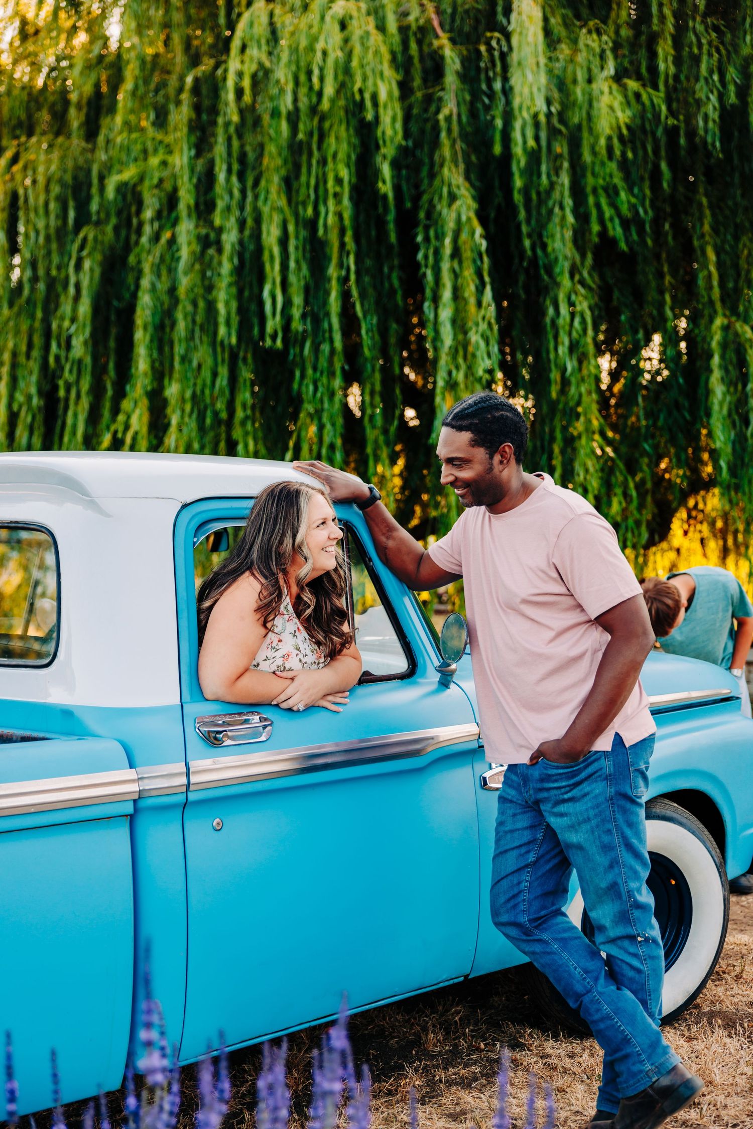 A romantic sequence of photos showing a couple posing with a light blue classic car against a backdrop of willow trees.