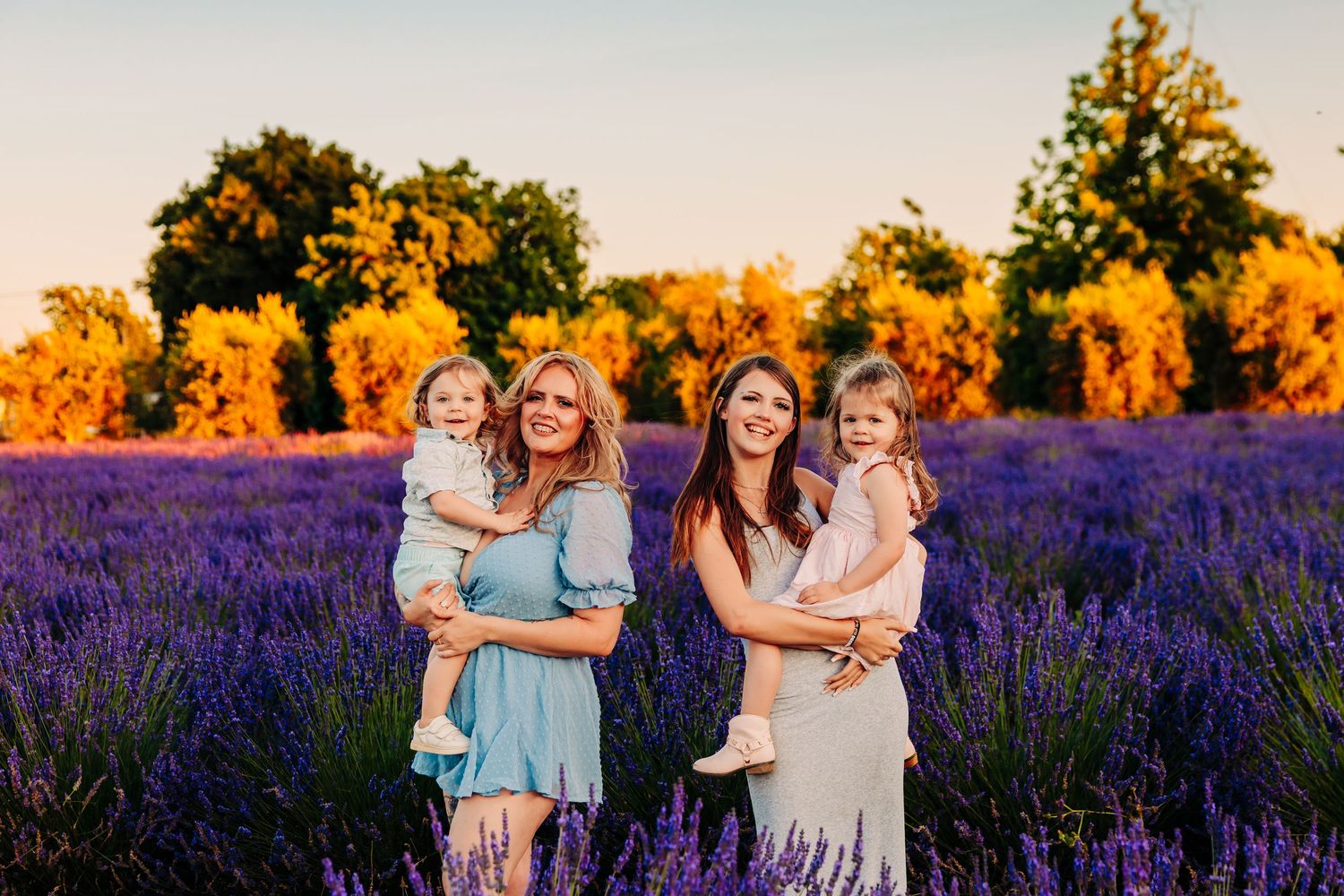 A family group embraces and laughs together in a vibrant purple lavender field at golden hour.