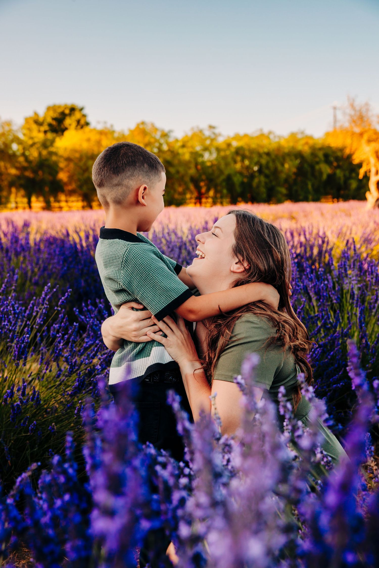 A romantic couple shares tender moments in a vibrant field of purple lavender flowers at golden hour.