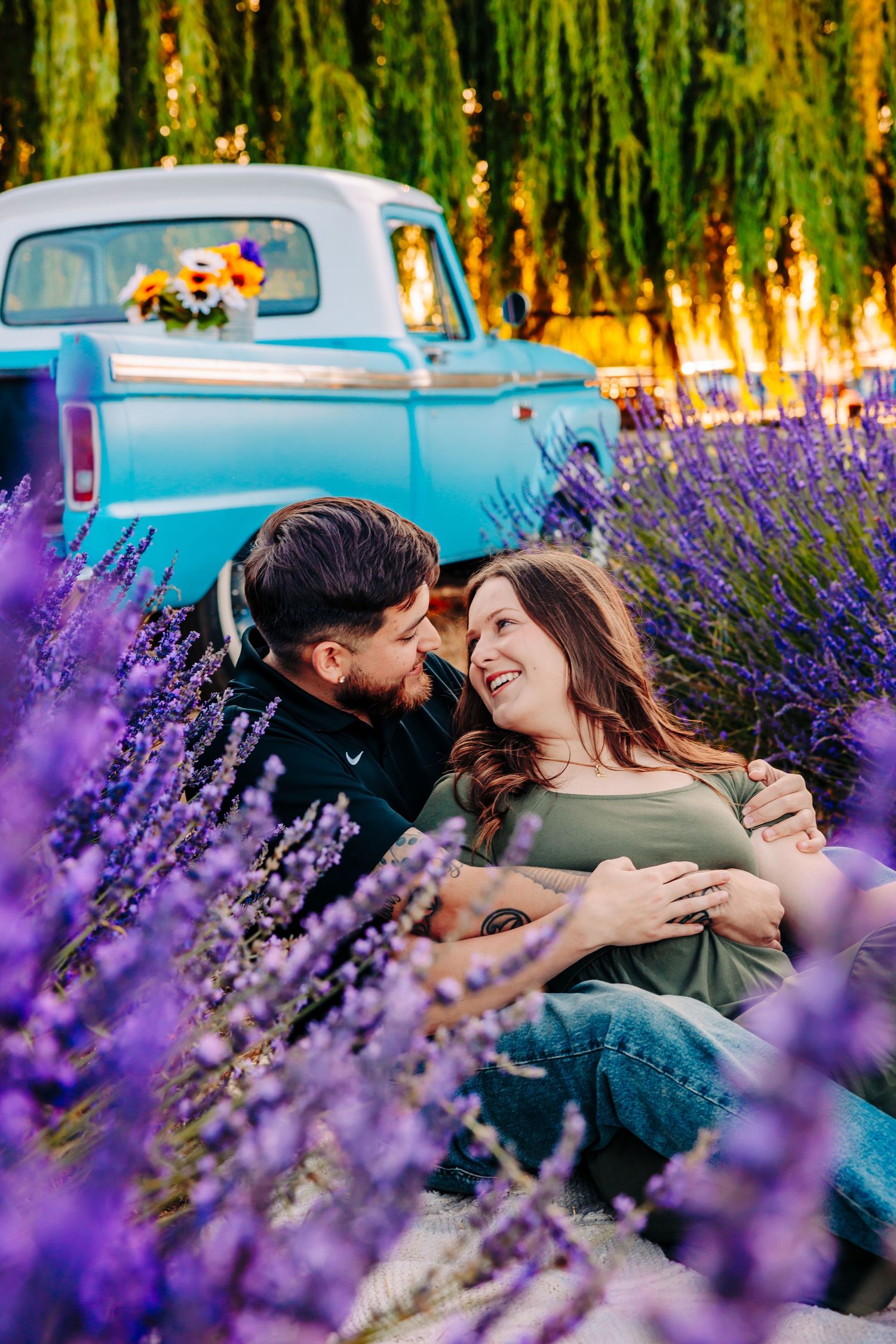 A romantic moment in a lavender field with a vintage blue pickup truck and willow trees in the background.