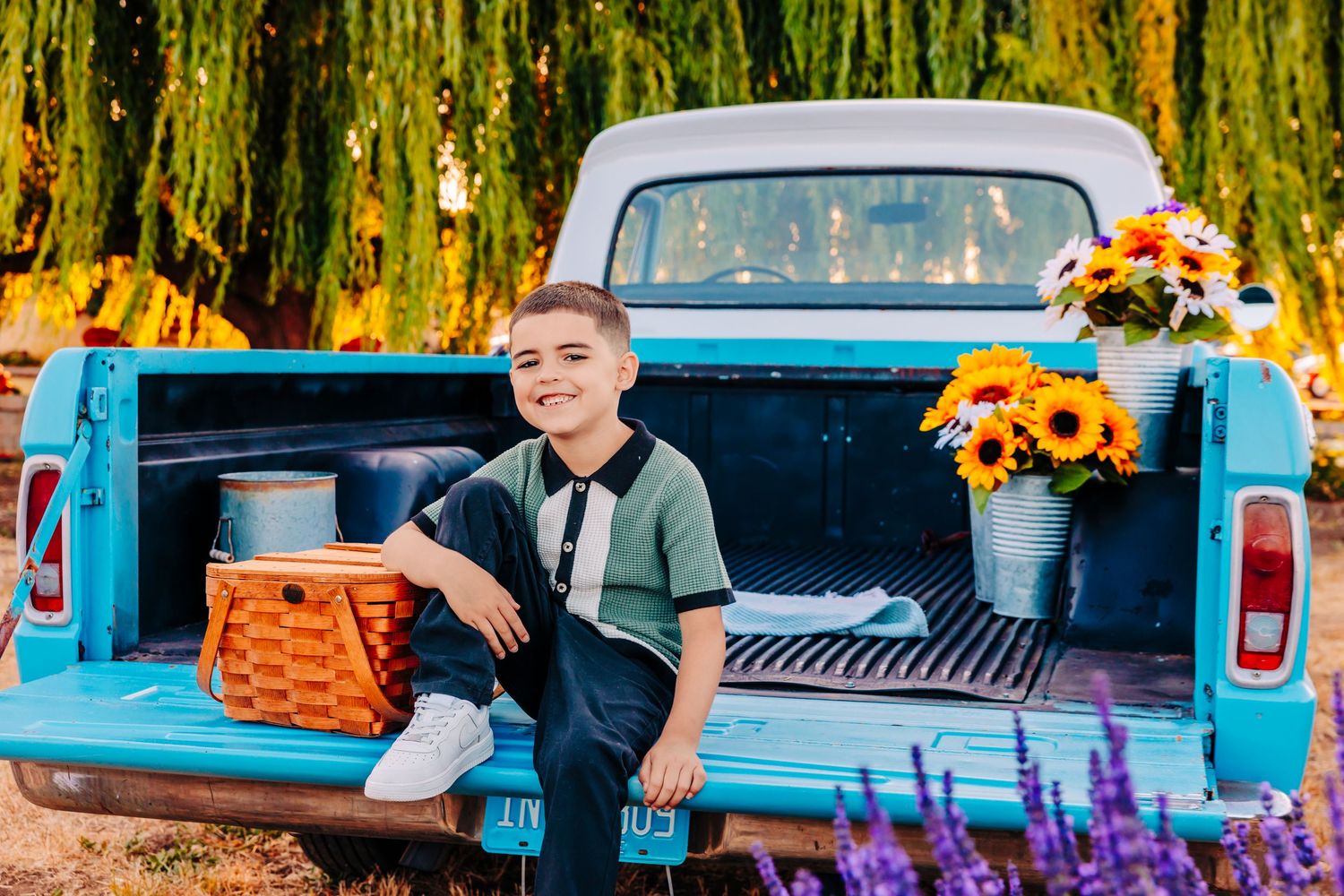 Colorful fall wedding decor with sunflowers and purple flowers arranged in vintage blue pickup truck bed.