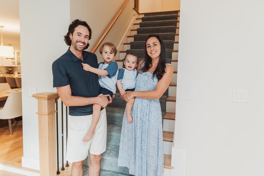 Family enjoying a candid moment together on stairs inside their bright modern home.