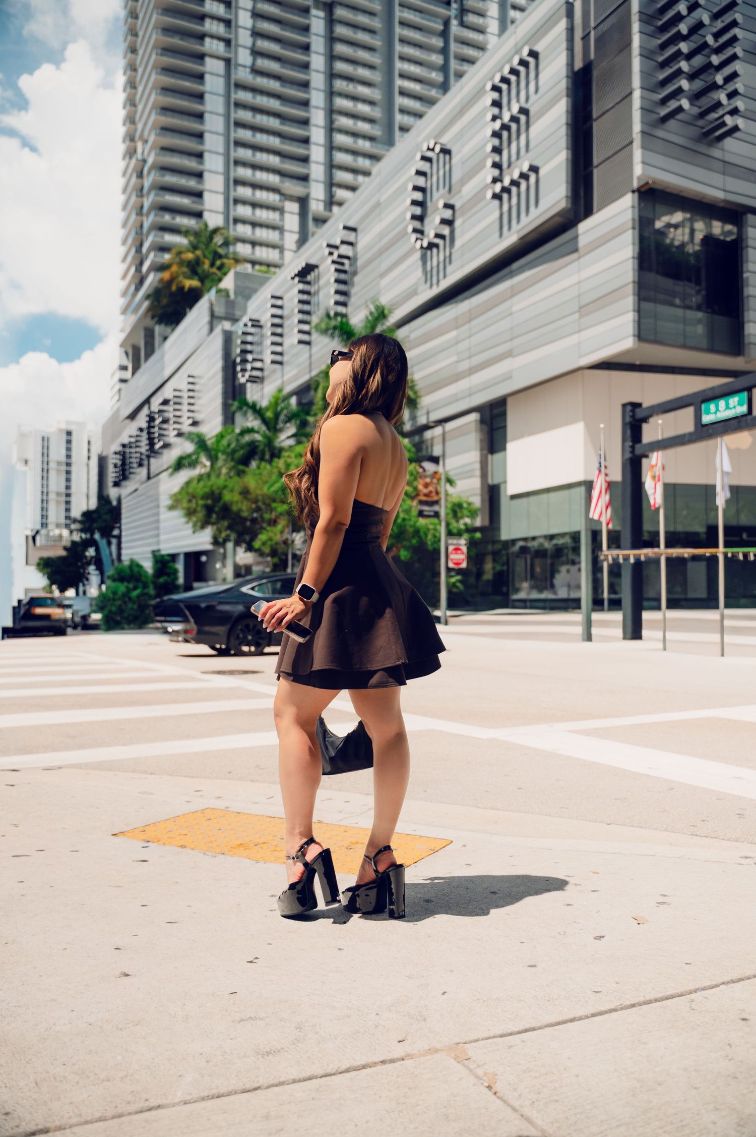 A series of urban fashion photos showing someone in black athletic wear crouching near modern buildings.