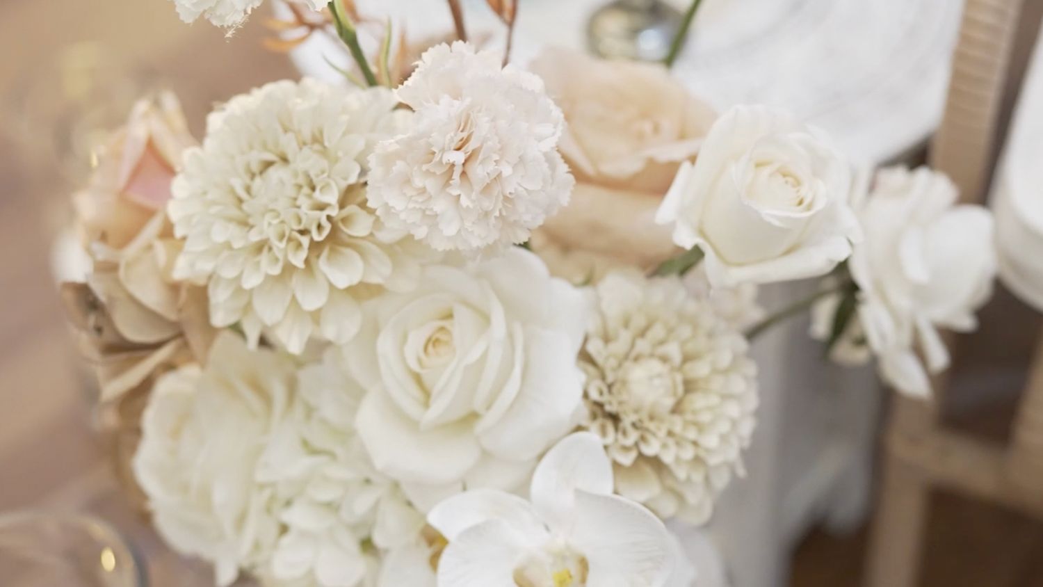 Elegant white floral arrangement featuring roses and dahlias in soft natural light.