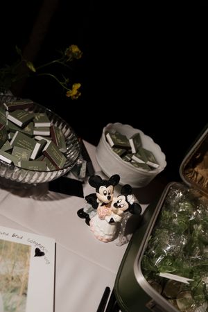 Wedding cake table decorated with Mickey and Minnie Mouse cake toppers and glassware.