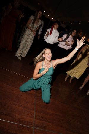 Guest in a green dress dancing enthusiastically on the wooden dance floor.