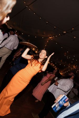 People dancing energetically at a dimly lit party with string lights overhead.