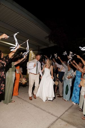 Wedding guests wave white napkins during the newlyweds' grand exit at an evening reception celebration.