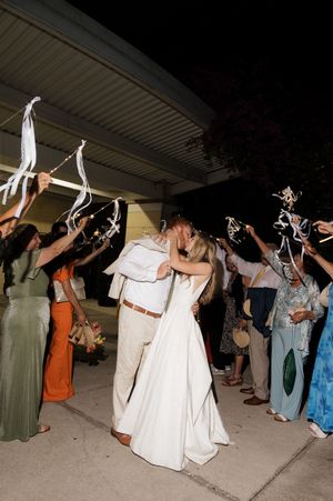 Wedding party and guests wave sparklers during nighttime send-off celebration.