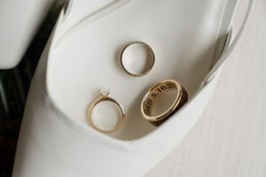 Gold wedding rings and engagement ring arranged in a minimalist composition on white ceramic plates.
