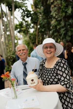 Wedding guests enjoy refreshments at a round table during an outdoor garden reception.