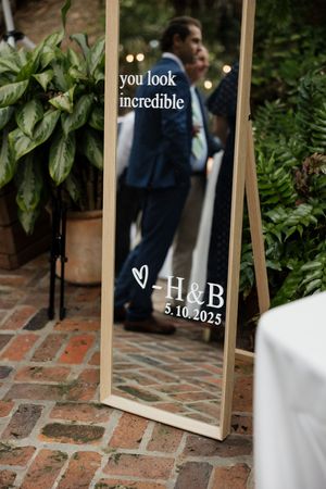 Wedding details showing mirrors with text and date 5.10.2025 displayed on brick pavers.