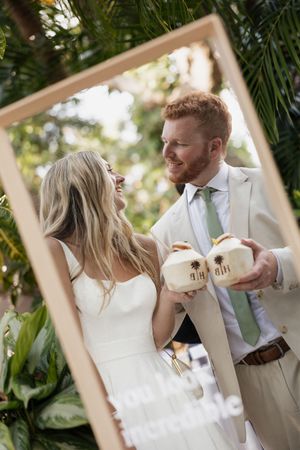 A couple shares a playful moment during their wedding photoshoot in an outdoor garden setting.