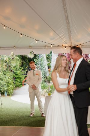 Romantic outdoor wedding reception under a white tent with string lights and floral decor.