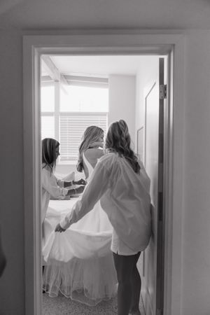 Wedding dresses being moved and arranged in a bright interior space.