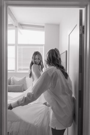 Multiple figures in white clothing dance and move gracefully through a bright interior hallway space.