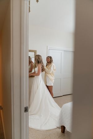 Wedding preparations through a doorway showing flowing white gowns.