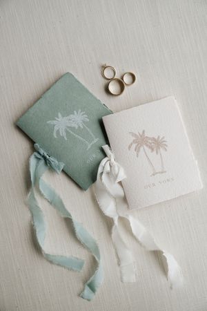 Wedding invitation suite featuring palm tree designs in soft sage green and cream colors with silk ribbons.