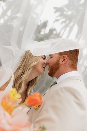 A romantic moment captured under flowing white fabric with soft floral accents.