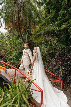 A couple walks down red-railed garden steps with a flowing white dress trailing behind.