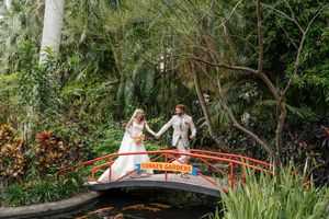 A wedding couple explores garden pathways surrounded by tropical greenery.