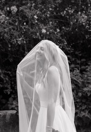 Ethereal black and white photograph of flowing wedding veil against dark foliage.