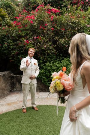 A couple shares a first look moment in a garden setting with bright bougainvillea flowers.