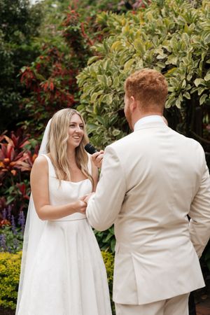 Couple in white attire dancing together in a garden setting.