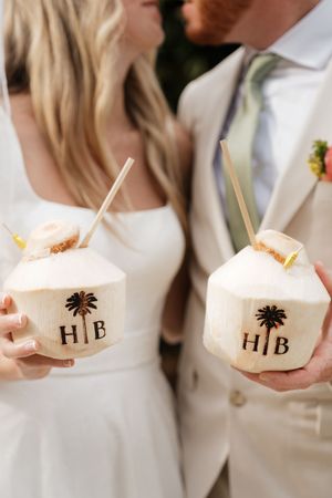 Tropical coconut drinks with HIB monogram and palm tree designs served at a beachside wedding celebration.