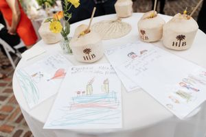Children's drawings and artwork displayed on a white table at a wedding reception.