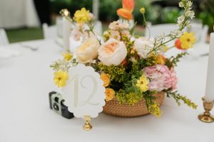 Delicate floral centerpieces featuring peach, yellow and white blooms arranged in rustic vessels.