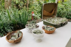 Succulent plants displayed in rustic bowls and pots on a white table in an outdoor garden setting.