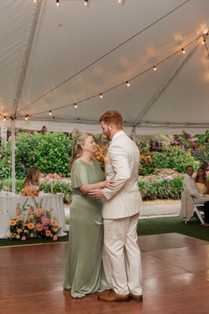 Wedding dance floor under white tent with string lights and floral decorations.