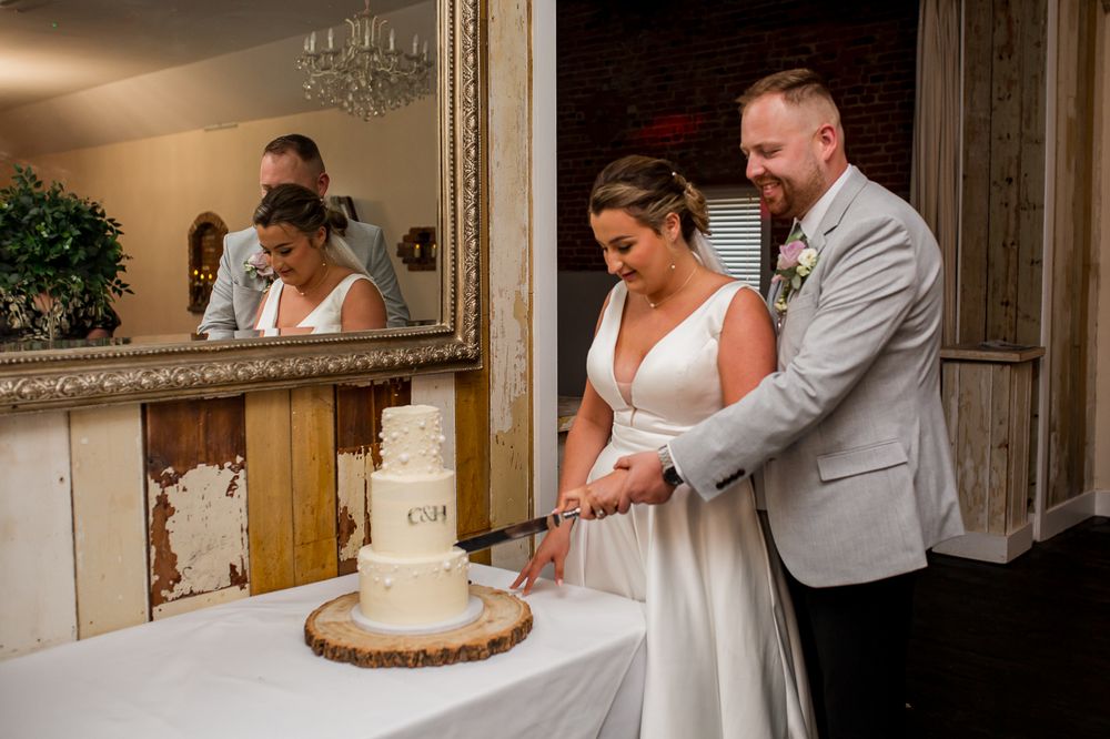 Wedding cake cutting scene with rustic wooden display stand.
